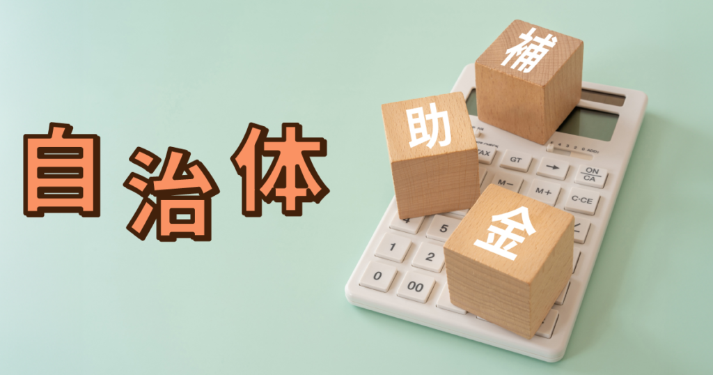 「補助金」と書かれた積み木の下に電卓が置かれている様子。自治体の補助金のイメージ画像。