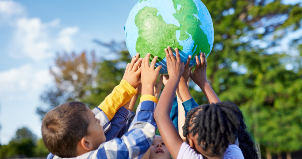 子どもたちが１つの地球儀を掲げている写真。